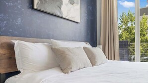 Un dormitorio con una cama grande, cabecera de madera y vistas a árboles a través de una ventana.