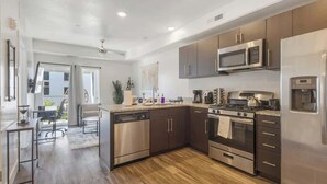 Une cuisine moderne dotée d’appareils électroménagers en acier inoxydable, de meubles de rangement en bois foncé et d’un plancher en bois.