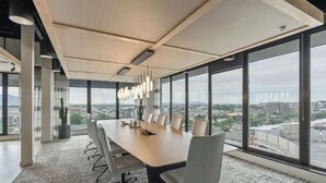 Une salle de conférence dotée d’une longue table, de chaises et offrant une vue sur la ville grâce à de grandes fenêtres.