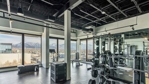 Une salle de sport équipée de matériel de musculation, dotée de grandes fenêtres et offrant une vue sur les montagnes.