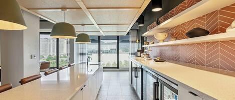 Una cocina moderna con una encimera larga, iluminación colgante y vistas a la ciudad.