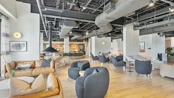 A spacious office with modern furniture, a high ceiling with exposed ductwork, and a mix of seating areas.