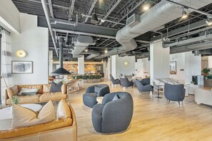 Una oficina amplia con muebles modernos, un techo alto con conductos expuestos y una variedad de espacios de estar.