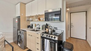 Cocina compacta con lavadora, estufa, microondas y pileta.