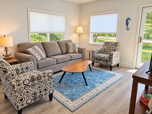 A living room with a sofa, patterned armchair, coffee table, and a rug.