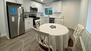 Een moderne keuken met witte kasten, roestvrijstalen apparatuur en een ronde tafel met stoelen.