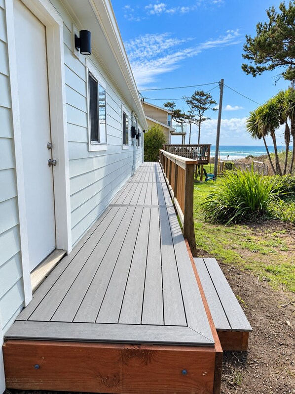 A wooden deck leading to a house with a view of the ocean.
