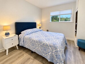 Un dormitorio con cama, mesitas de noche, un ventanal y vistas al exterior.