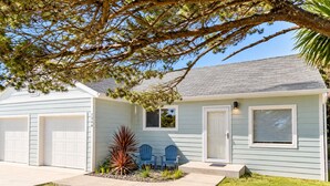 A single-story house with a garage, a front door, and a small porch area with two chairs. - Salty  Seahorse (Waldport)