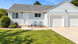 A single-story house with a garage, a front porch with two chairs, and a well-maintained lawn. - Salty Crab  - Ocean View (Waldport)