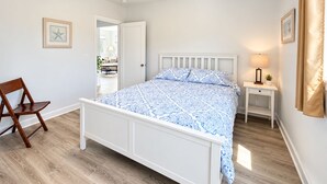 A bedroom with a bed, a chair, a nightstand, and a lamp. - Salty Crab  - Ocean View (Waldport)