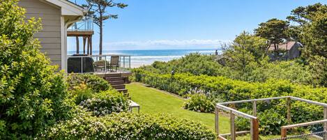 A residential property with a deck overlooking a landscaped garden and a view of the ocean.