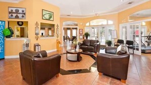 A spacious lobby with a massage service counter, leather sofas, a coffee table, and a view of the gym area. - Townhome Perfectly Located Near Clubhouse (Kissimmee)