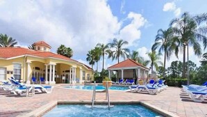 A pool area with lounge chairs and a building with a red roof. - Townhome Perfectly Located Near Clubhouse (Kissimmee)