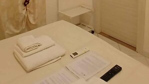 Egy szállodai szoba, amelyben található egy ágy, egy falra szerelt, síkképernyős televízió, egy ajtó és egy légkondicionáló berendezés.