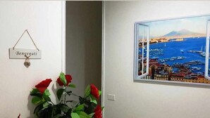 Egy szoba, ahonnan a kikötőre nyílik kilátás, egy „Benventu” felirat és egy vörös virágokkal díszített, virágtartóban elhelyezett n övény található benne.