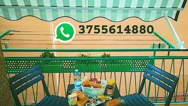 Egy erkély, ahol egy asztalra ételt és italt helyeztek, egy zöld szék áll, és egy telefonos elérhetőség van a fölé kiírva.