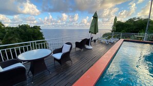 A deck with outdoor seating, a pool, and a view of the ocean.