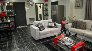 A modern living room with two white sofas, a glass coffee table, and a black tiled floor.