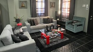 A living room with a sofa, armchair, and a coffee table with books and decorative items.