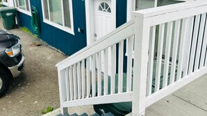 A residential building with a blue exterior, white trim, and a white front porch with a railing. - Last frontier Rental Family #1 (Anchorage)