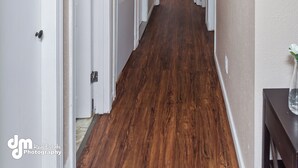 A hallway with wooden flooring, white doors, and beige walls. - Last frontier Rental Family #1 (Anchorage)