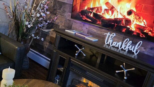 A fireplace with a TV above it, a sign that says 'thankful,' and a plant on the side. - Last frontier Rental Family #1 (Anchorage)