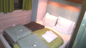 Une petite pièce, de taille modeste, avec un lit superposé, une fenêtre avec des rideaux et une tête de lit en bois.