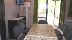 Un coin repas avec une table recouverte d’une nappe aux motifs de café, entourée de chaises.