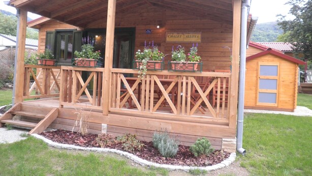 Un bâtiment en bois doté d’un porche, de plantes en pot et d’une enseigne sur laquelle on peut lire « CHALET ALLOYA ».