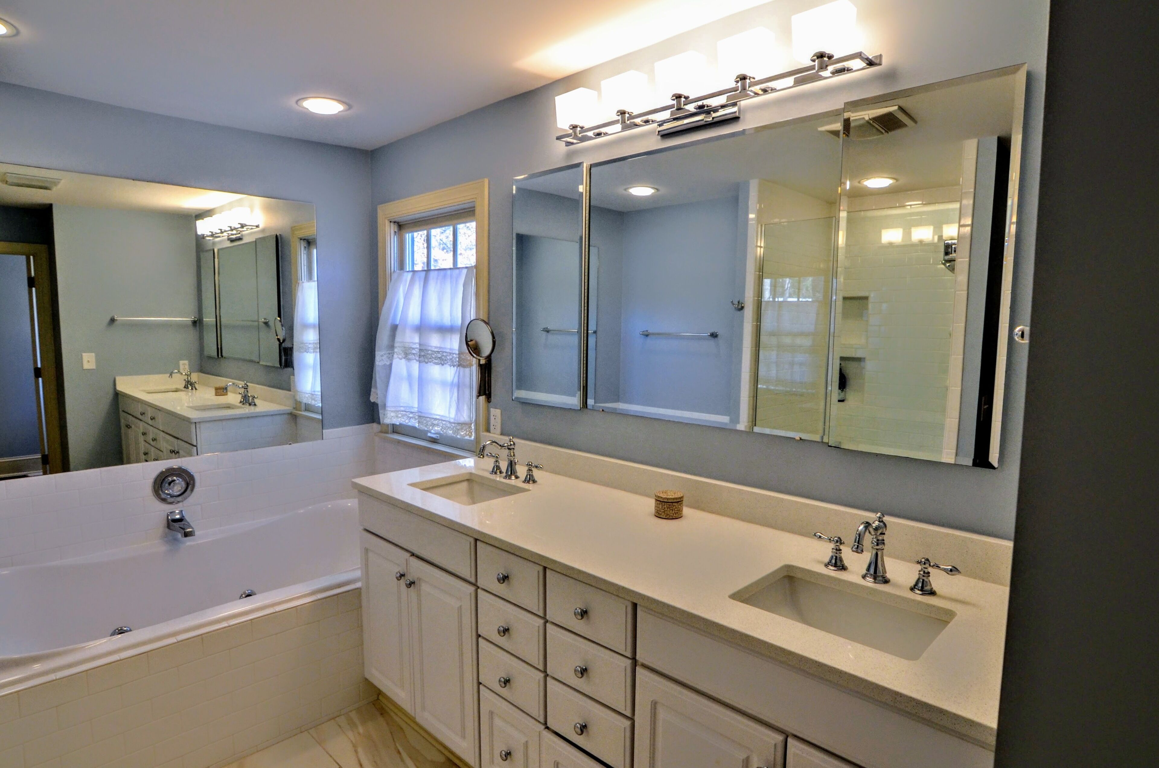 Une salle de bain moderne avec une grande baignoire, deux lavabos et un meuble-lavabo avec des tiroirs.