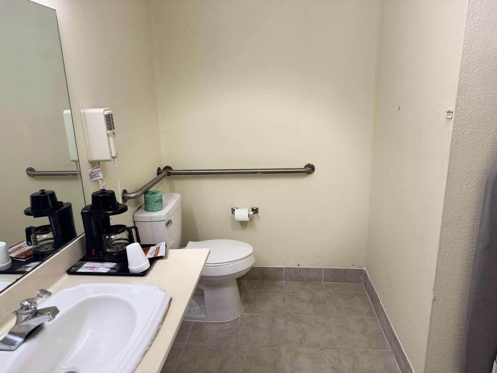 Une petite salle de bain compacte avec un lavabo blanc, des toilettes et un miroir.