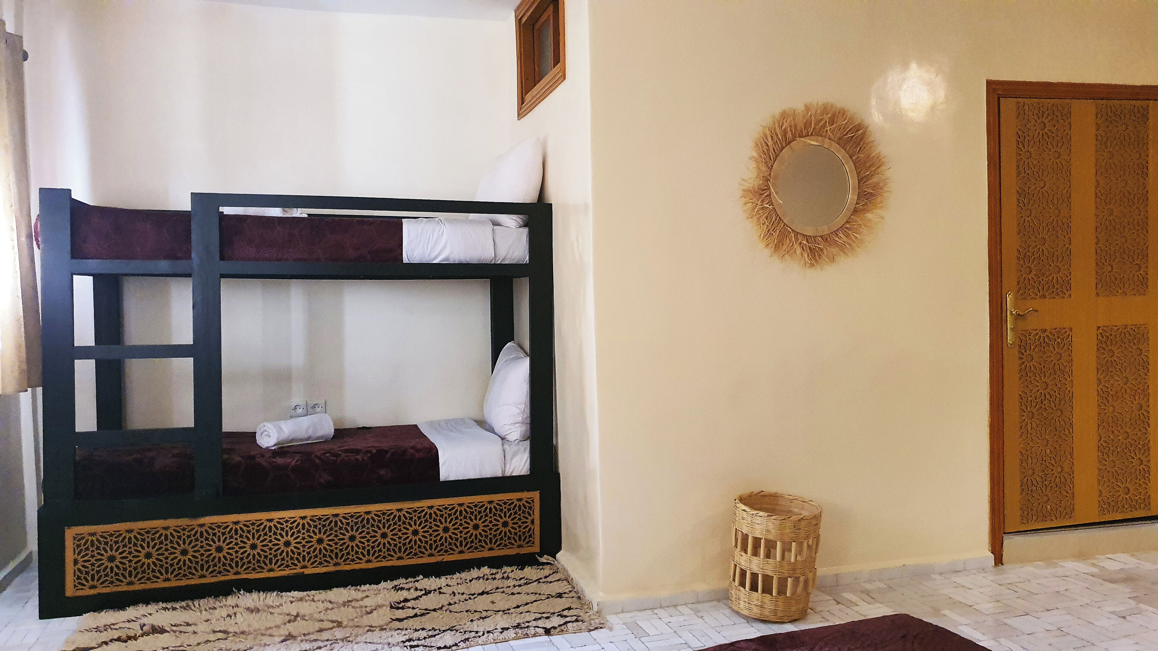 A bunk bed with a decorative headboard, a wicker basket, and a door with intricate carvings.