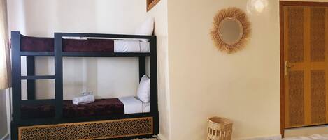 A bunk bed with a decorative headboard, a wicker basket, and a door with intricate carvings.
