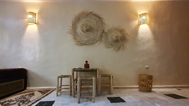 Una habitación con una mesa redonda, cuatro sillas, dos lámparas de pared y un adorno en la pared.