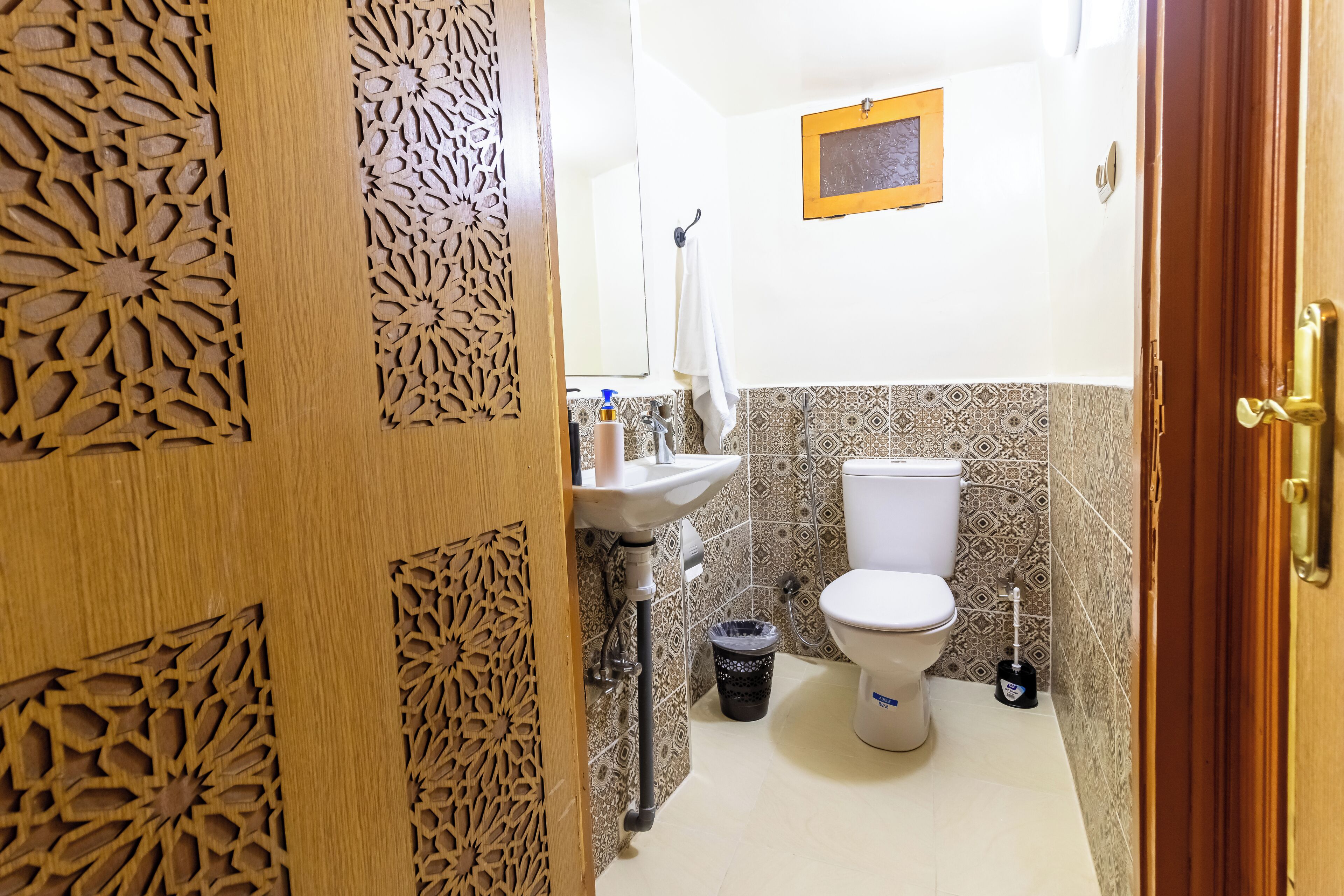A bathroom with a sink, toilet, and decorative wooden paneling.