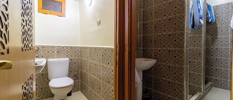 Ein Badezimmer mit Toilette, Waschbecken und Duschbereich.