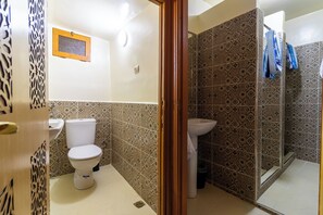 Bathroom features a pedestal sink, toilet, and glass-enclosed shower area.