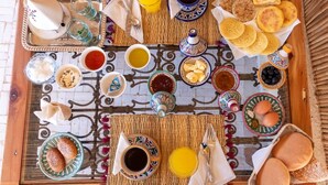Un desayuno servido sobre una estera tejida con diferentes platos y bebidas.