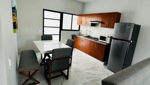 Una cocina moderna con armarios de madera, un refrigerador de acero inoxidable y un comedor con piso de mármol.