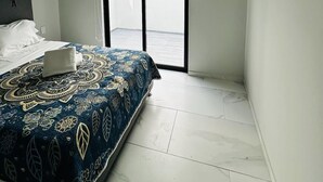 Un dormitorio con cama, ventilador de techo, ventana con persiana y vista al exterior.