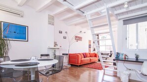 A modern living room with a round dining table, a red sofa, and a white desk. - TERRACE DUPLEX at SAGRADA FAMILIA/GRACIA (Barcelona)