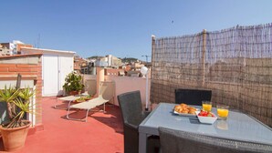 A rooftop terrace with a table set for breakfast, including croissants, fruit, and orange juice. There are potted plants and outdoor chairs. - TERRACE DUPLEX at SAGRADA FAMILIA/GRACIA (Barcelona)