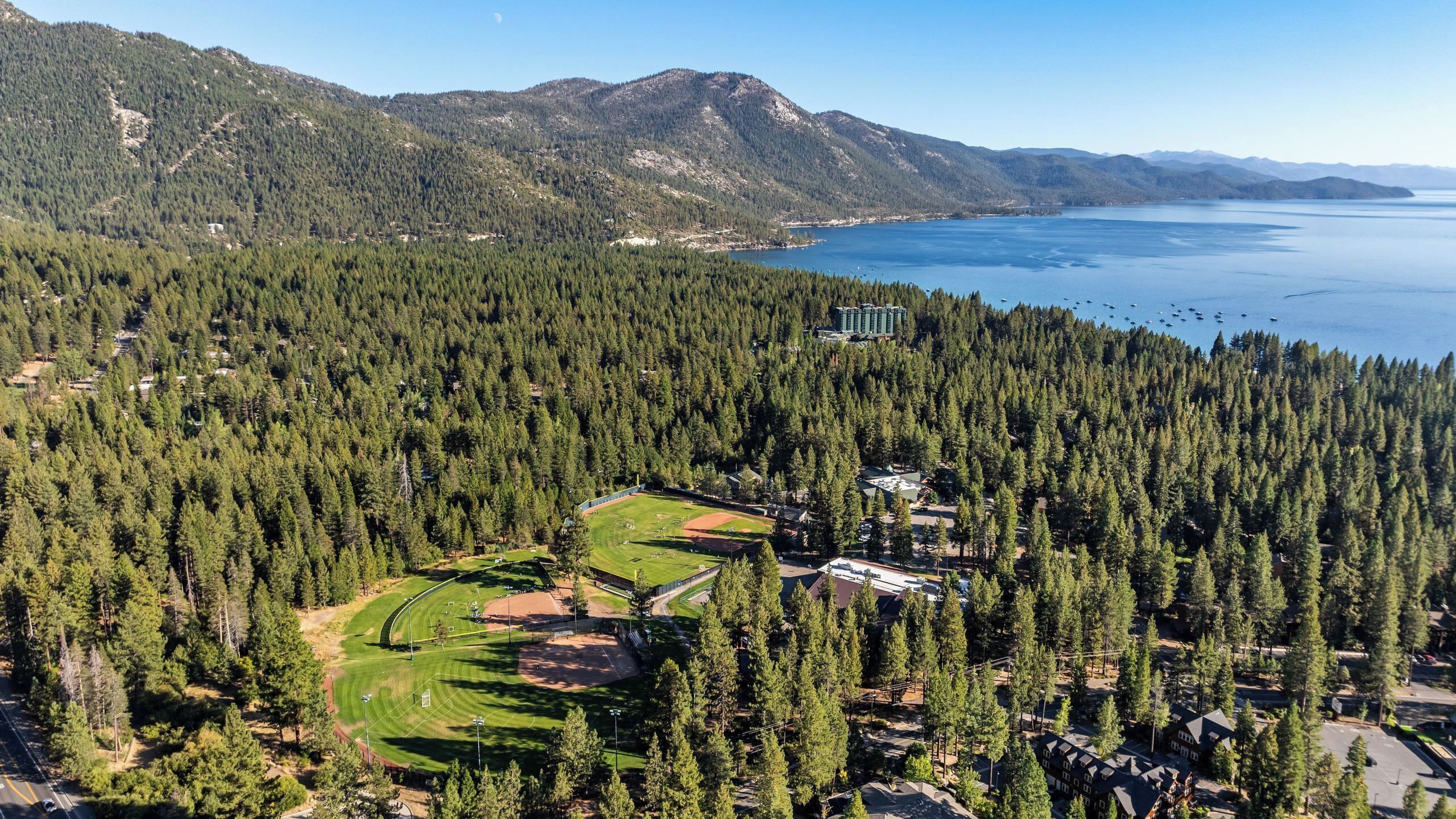 A mountainous landscape with a lake, dense forest, and a golf course.