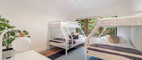A room with bunk beds, a desk, a potted plant, and a hanging light fixture.