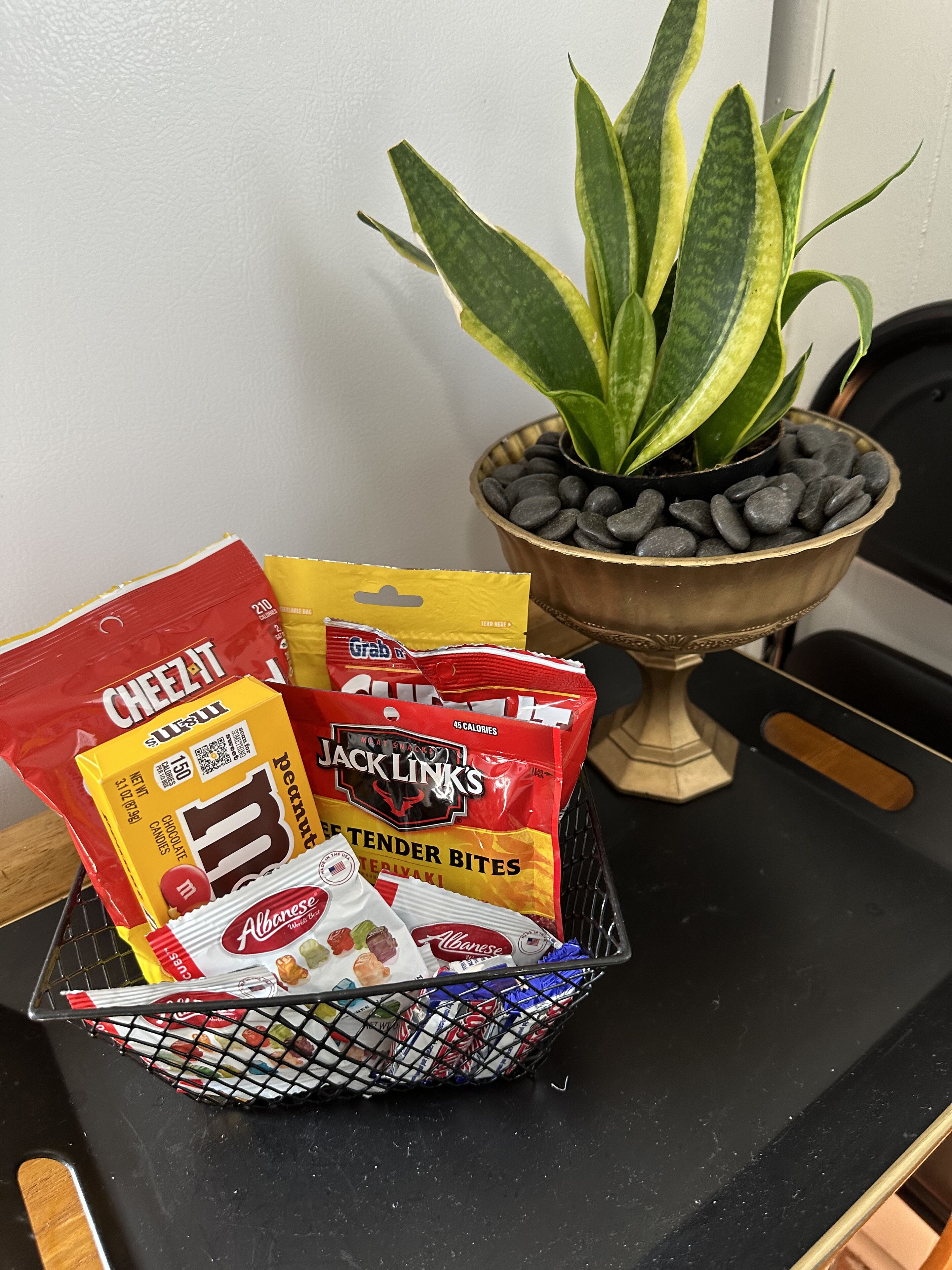 Eine Auswahl an Snacks, ein Blumentopf und ein dekorativer Gegenstand auf einer Tischplatte.