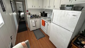 Una cucina compatta con mobili bianchi, un frigorifero, un forno a microonde e un lavandino.