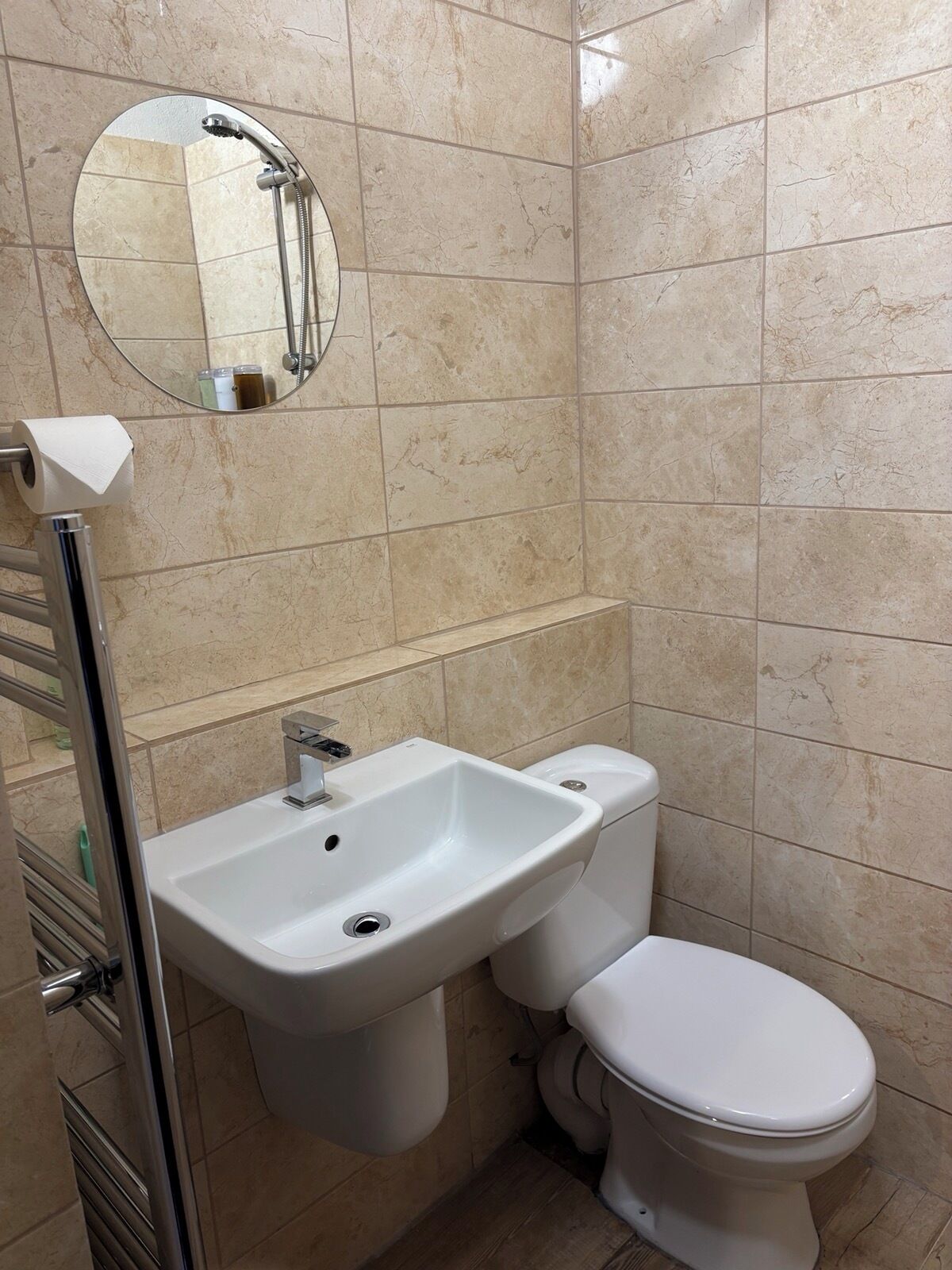 A bathroom with a white sink, toilet, and a round mirror on the wall.