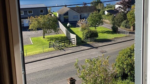 A residential area with houses, a grassy lawn, and a view of a lake and mountains. - Highland Rooms - Room Only No Breakfast (Ullapool)