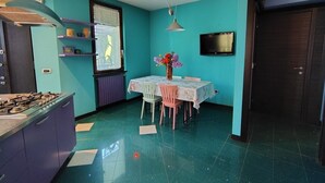 A kitchen with teal walls, a gas stove, a table with chairs, and a vase with flowers.